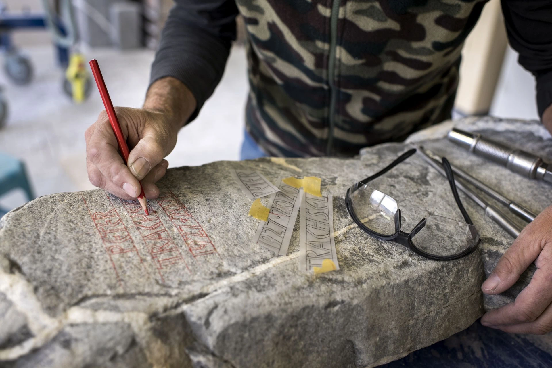 Steinmetz in Thun skizziert per Hand die Beschriftung für einen Grabstein aus Naturstein – traditionelle Bildhauerarbeit in der Region Bern.